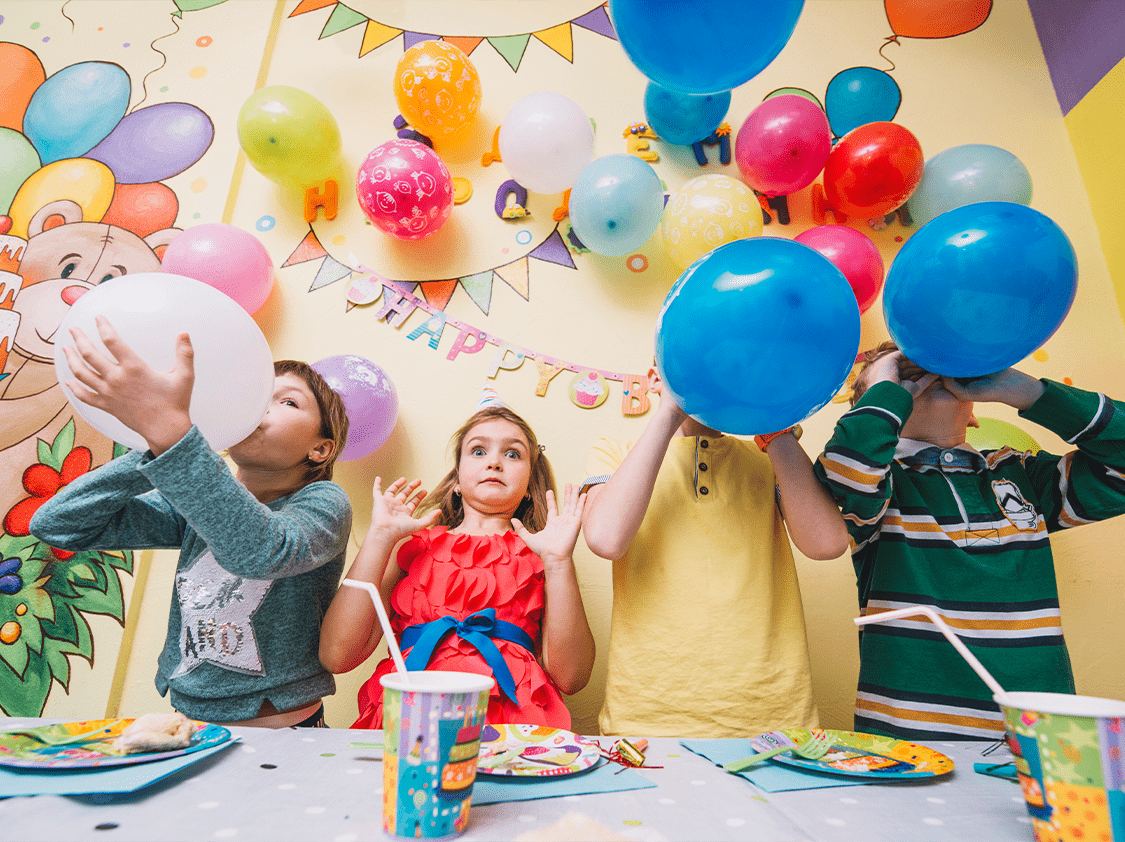 الأطفال يستمتعون بتضخيم البالونات في حفلة عيد ميلاد مليئة بالألوان والمرح.