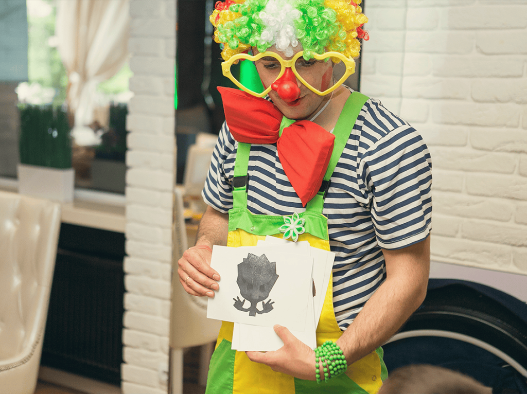 A clown entertaining kids at a birthday party with games and fun activities, wearing colorful costume and glasses.